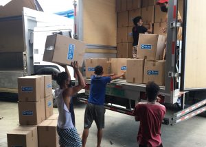 Loading boxes of relief aid onto trucks for distribution to typh